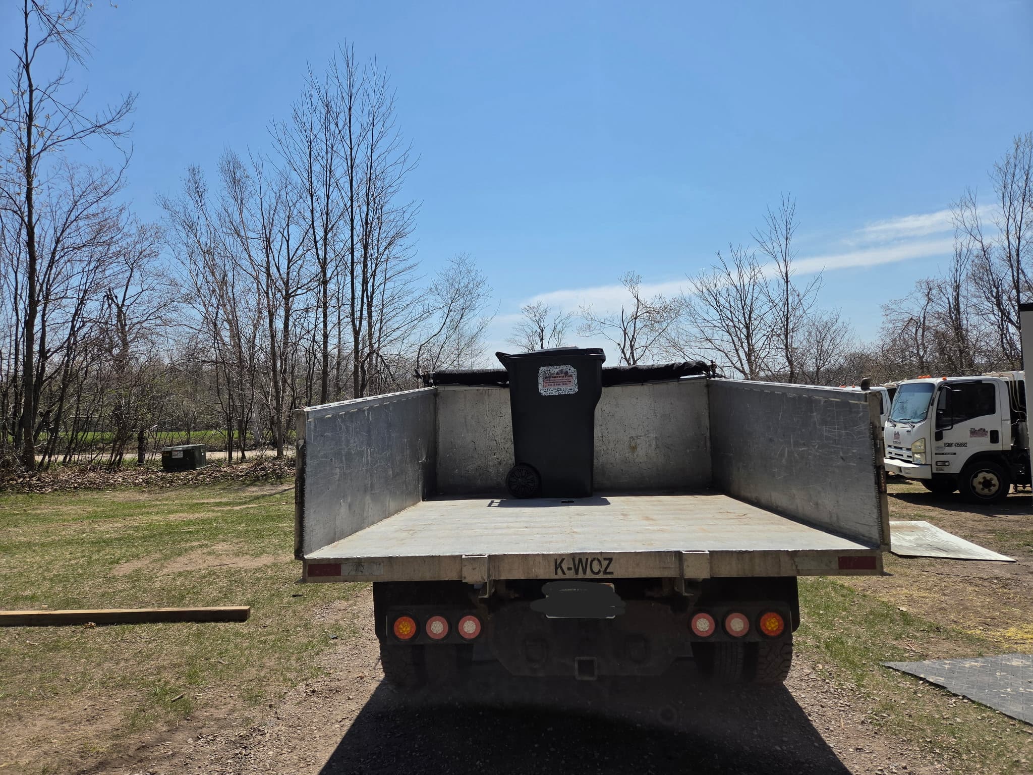 The back of the JMT Sanitation dump truck with a single tote inside, showing roughly 7-8 cubic yards of capacity.