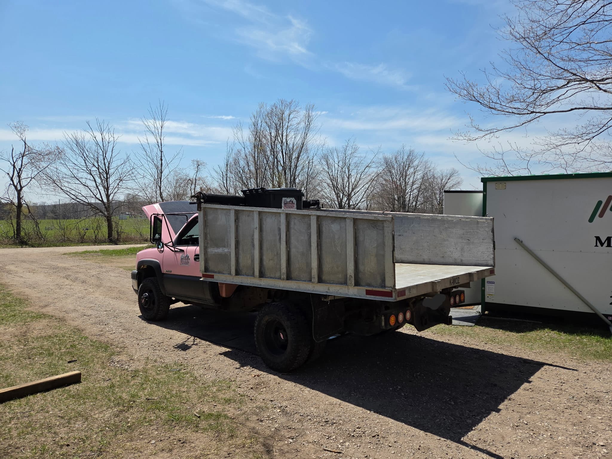 JMT Sanitation pink dump truck parked, ready for a bulk haul.