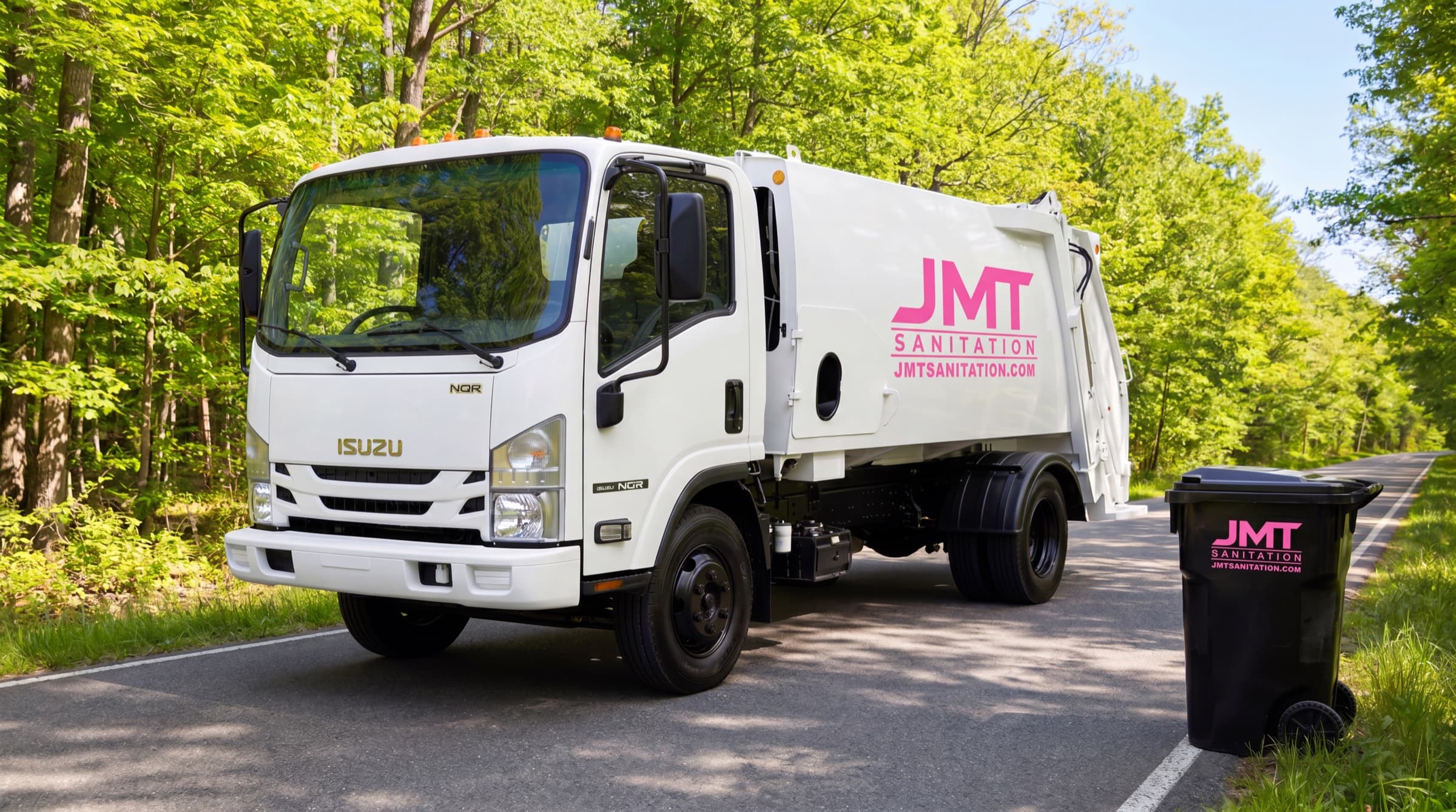 A JMT Sanitation truck pulled up next to a residential garbage tote on a tree-lined Emmet County road.